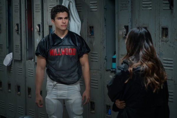 A football player talks to a girl with her back to the camera in a lockerroom