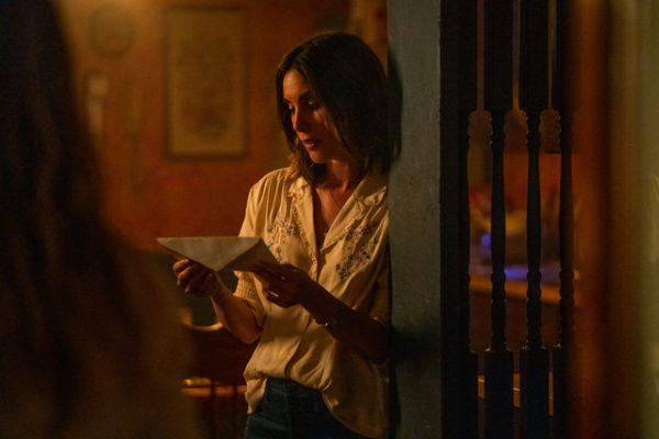 A brunette woman looks at an envelope