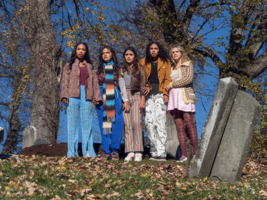 Five girls stand in a graveyard