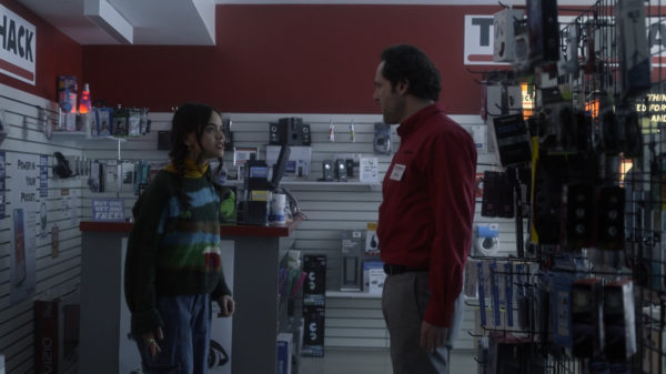 A teen girl confronts a man in a red shirt in an electronics store