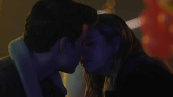 A boy (L) and girl (R) kiss in close up