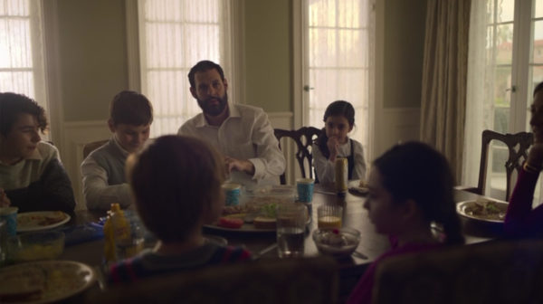 A Jewish Orthodox man serving his children at the dinner table