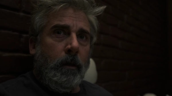 A bearded man (Steve Carell) in dark close-up