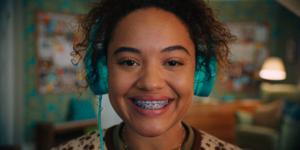 A girl with braces and headphones smiling at the camera