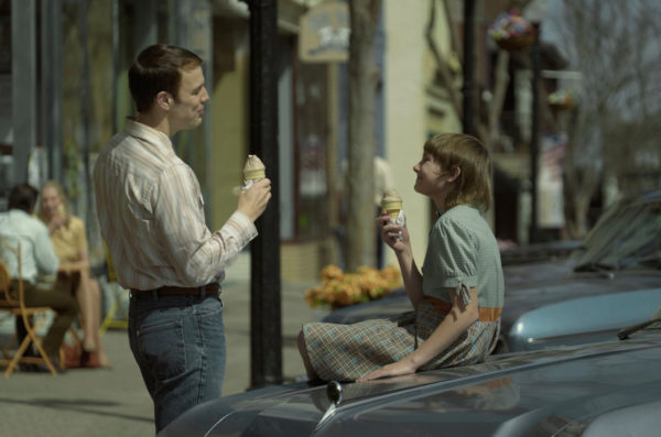 A man (l) and a pre-teen girl (r) eat ice cream on the hood of a car