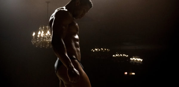 A nearly naked bodybuilder (Jonathan Majors) posing in profile