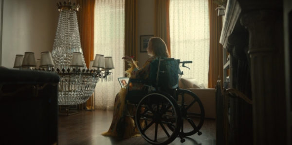 Dorothy (Lauren Ambros) sitting in a wheelchair in front of a fallen chandelier