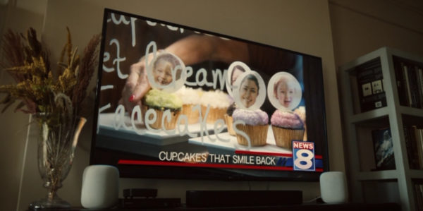 A TV still of children's faces stuck on cupcakes