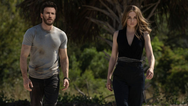 Chris Evans (L) in a grey t-shirt walks next to Ana de Armas (R) in a black jumpsuit