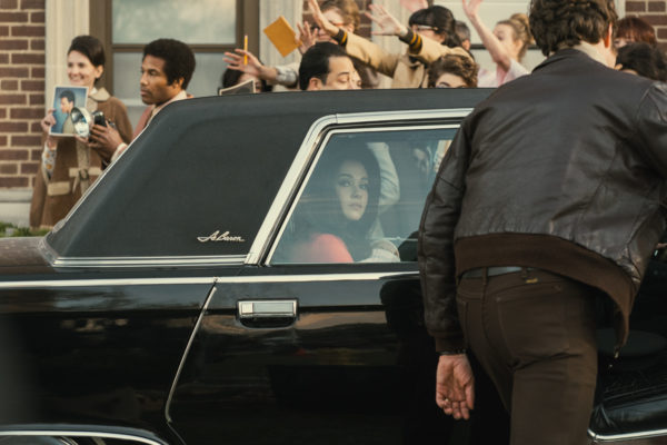 Priscilla (Cailee Spaeny) looks out of a limousine window at a throng of women