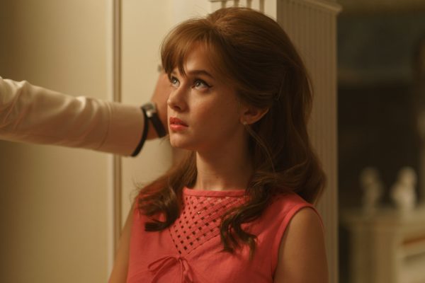 A teenage Priscilla (Cailee Spaeny) stands against a wall, boxed in by a man's arm