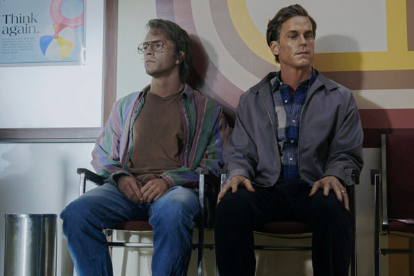 80s Tim (Jonathan Bailey - L) sits next to 80s Hawk (Matt Bomer - R)