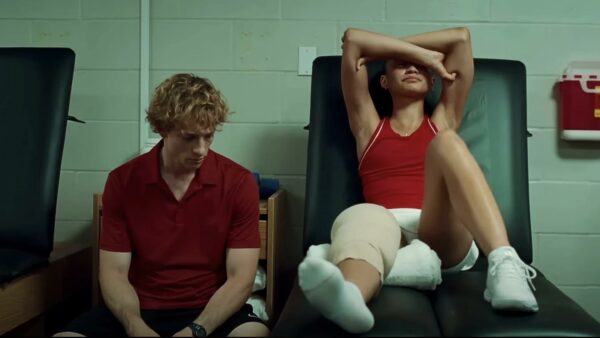 Art (Mike Faist) sits next to a stretched out, bandaged Tashi (Zendaya)