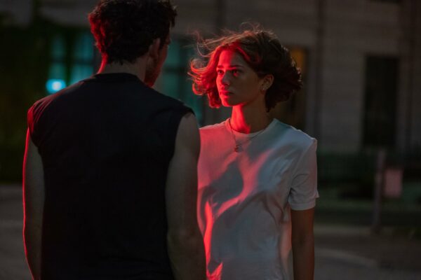 Patrick (Josh O'Connor) and Tashi (Zendaya) stand in a parking lot in red light