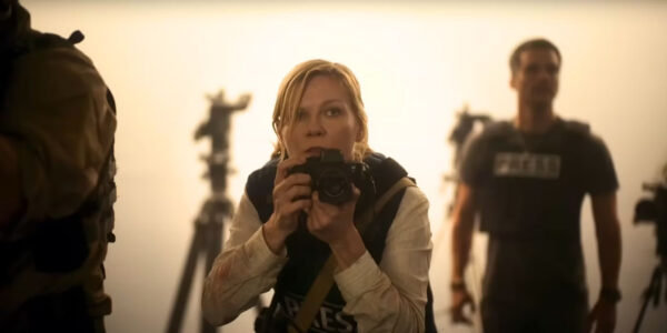 Lee Smith (Kirsten Dunst) kneels with her camera as Joel (Wagner Moura) watches behind her