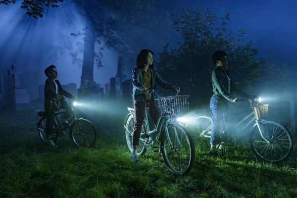 Three kids on bikes in a cemetery at night