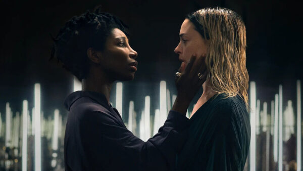 A Black woman caresses the chin of a Blonde woman with damp hair