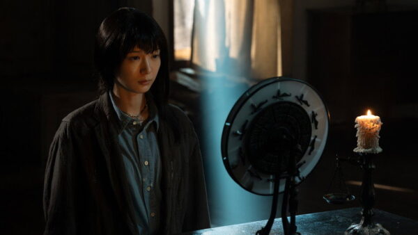 A Japanese woman with asymmetrical haircut stares into a circle on a table, illuminated from a beam of light from the window behind her head