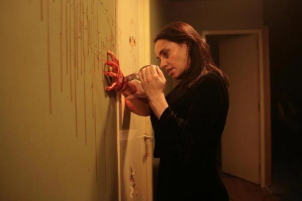 A still of Béatrice Dalle stabbing a hand with a pair of scissors