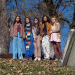 Five girls stand in a graveyard