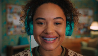 A girl with braces and headphones smiling at the camera