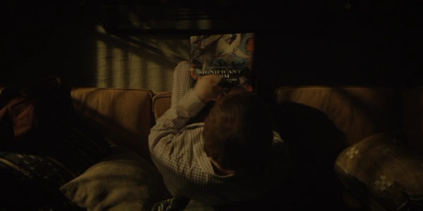 Overhead of Julian (Rupert Grint) reading a book in the dark