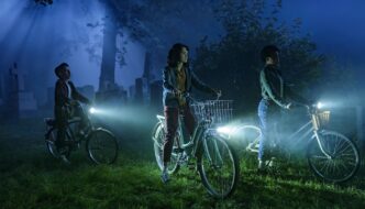 Three kids on bikes in a cemetery at night