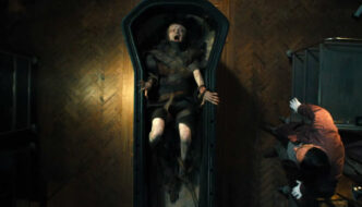 An overhead shot of a girl wrapped in dark bandages, screaming inside a sarcophagus